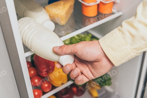Preview: cropped view of man taking bottle of milk out of fridge