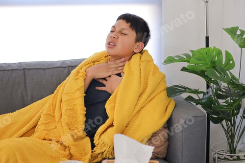 Preview: Young Boy Feeling Discomfort from a Painful Sore Throat, Seeking Warmth Under Cozy Blanket at Home