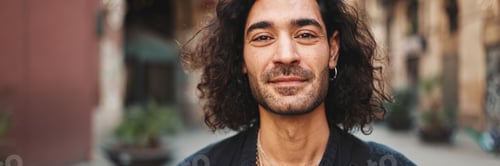 Preview: Young attractive italian guy with long curly hair and stubble looks into the camera and smiles