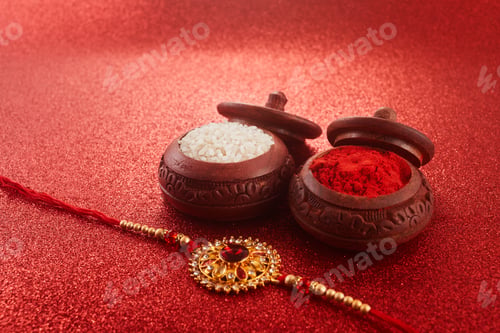 Preview: Raksha Bandhan. Rakhi string, Rice Grains and Kumkum on red background.
