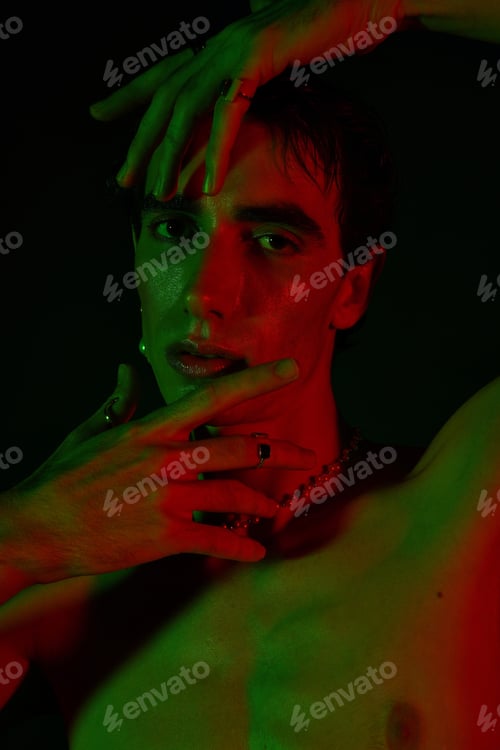 Preview: Stylish man poses dramatically under colorful lighting in a creative setup