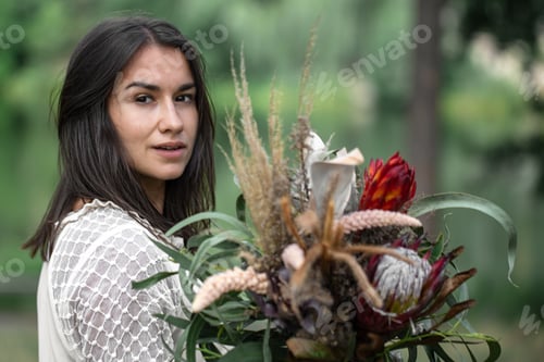 Preview: Portrait of an attractive young woman with a bouquet of exotic protea flowers.