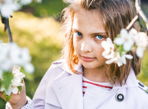 Preview: Little girl is walking in spring garder with apple trees and white flowers. Romantic stylish spring