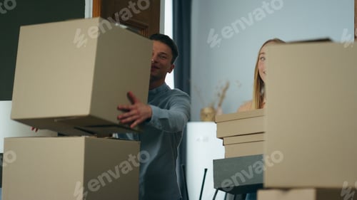 Preview: Family carrying cardboard boxes to new apartment. Couple excited by moving.