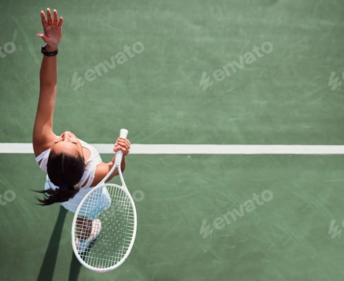 Preview: Game on. High angle shot of a young woman serving a ball while playing tennis on a court.