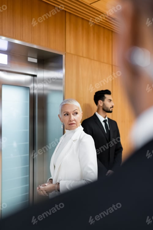 Preview: senior security man waiting for elevator near bi-racial bodyguard and african american security man