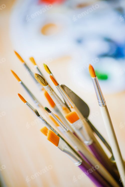 Preview: Close-up of various artist paintbrushes and a palette knife with a blurred background
