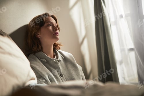 Preview: Young Adult Caucasian Woman Sitting Alone Reflecting near Window Feeling Sadness
