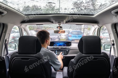 Preview: Man in car using touchscreen during rain. Modern car technology inside vehicle.