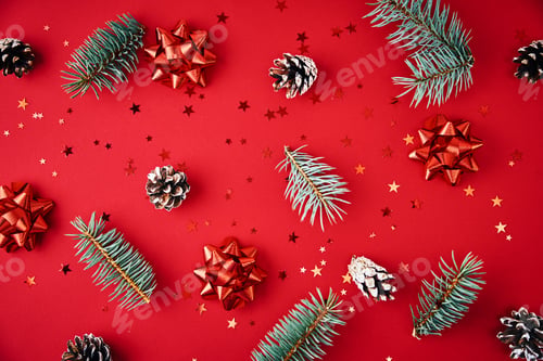 Preview: Fir branches, pine cones, dried fruits and festive confetti on a red background