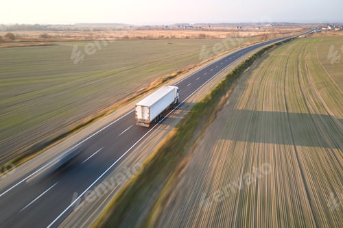 Preview: Aerial view of blurred fast moving semi-truck with cargo trailer driving on highway