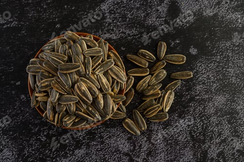 Preview: Sun Flower seed in a wooden bowl on the black cement floor.