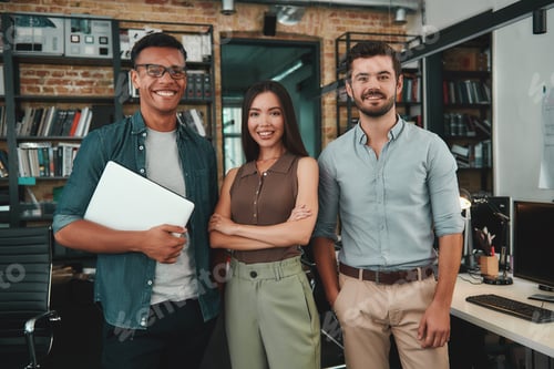 Preview: Happy to work together. Group of three cheerful young people in casual wear looking at camera with