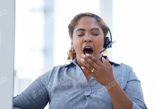 Preview: One african american call centre telemarketing agent yawning while working on a computer in an offi