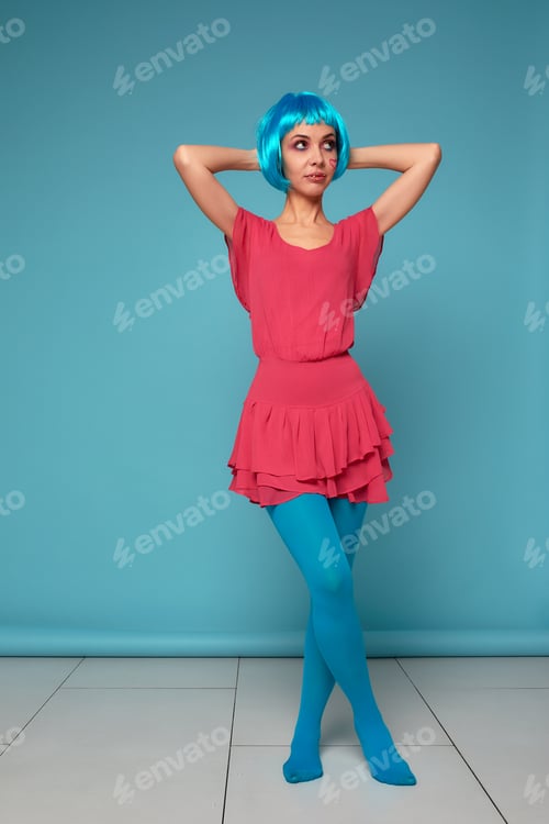 Preview: Close up of a flirtatious female model on blue background wearing a blue wig. Pretty glamorous woman