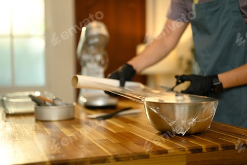Preview: Man wrapping a metal bowl with plastic wrap during the preparation of compound butter