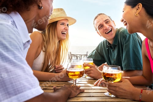 Preview: Multiracial friends laughing having fun at beach bar drinking beers. Friends on summer vacation.