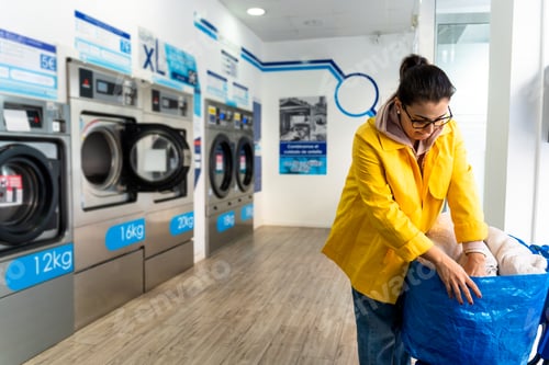 Preview: Woman doing laundry in the laundromat shop