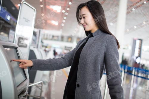 Preview: Businesswoman using ticket machine at the airport