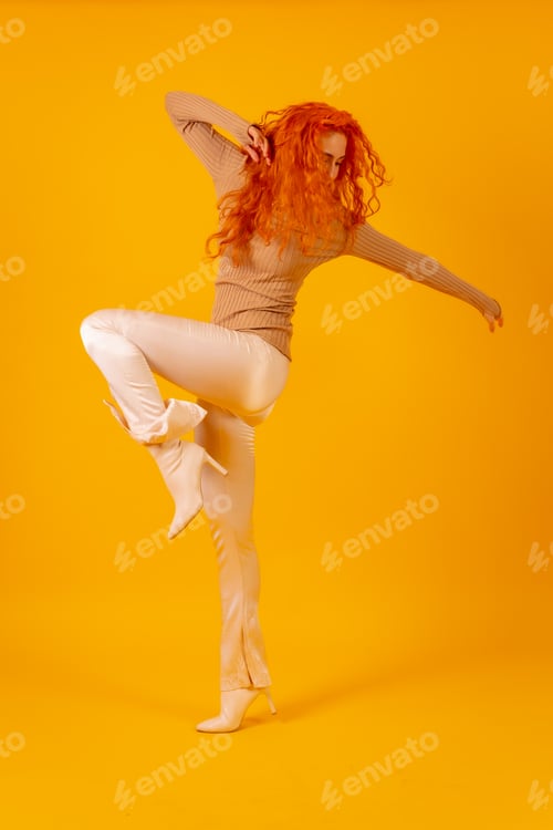 Preview: Red-haired woman on a yellow background, studio shot, fashion posed, full body in white boots
