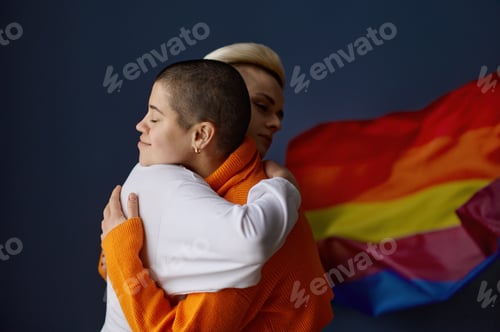 Preview: Portrait of positive lesbian woman in friendly embrace on rainbow flag