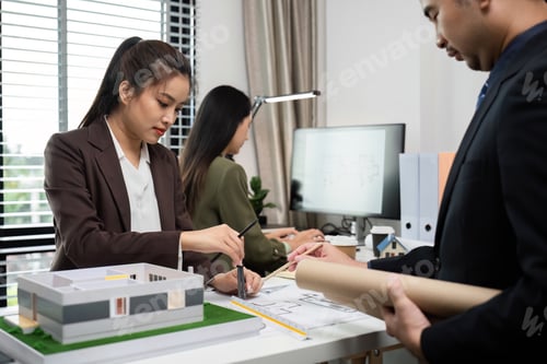 Preview: Business Team Discussing Real Estate Project with Architectural Model and Blueprints in Modern