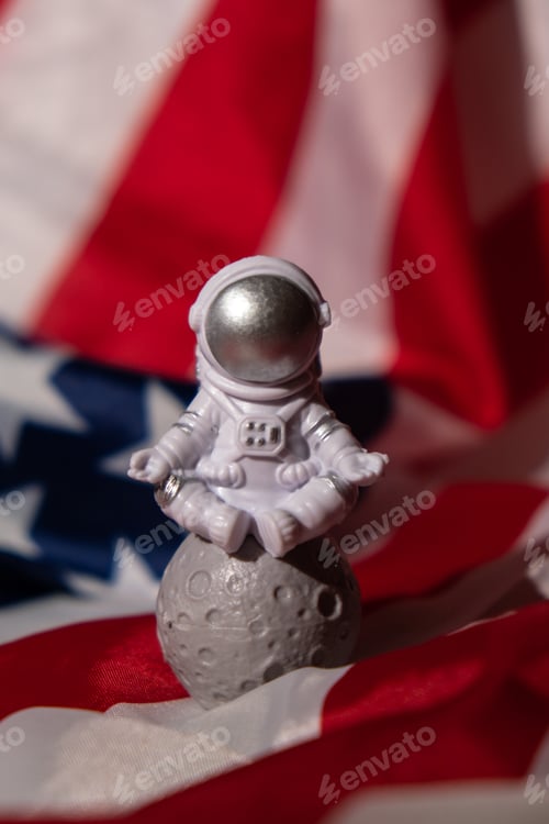 Preview: Plastic toy figure astronaut on American flag background Copy space. 50th Anniversary of USA Landing