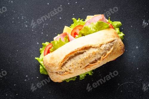 Preview: Ciabatta sandwich with lettuce, cheese, tomatoes and ham on black table.