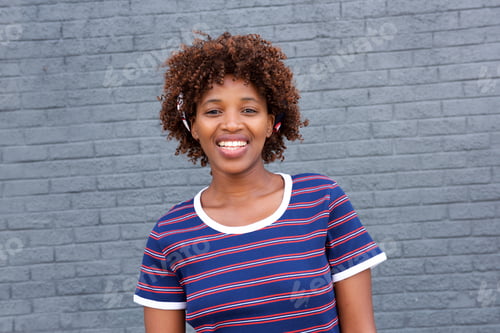 Preview: african woman in striped shirt smiling against gray wall