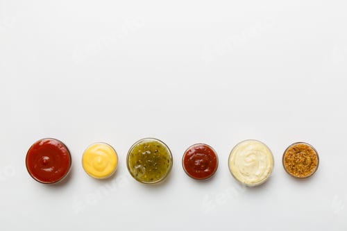 Preview: Different types of sauces in bowls on a colored Board . Top view. various sauces copy space