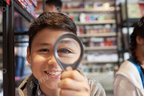 Preview: Boy with magnifier in library smiling