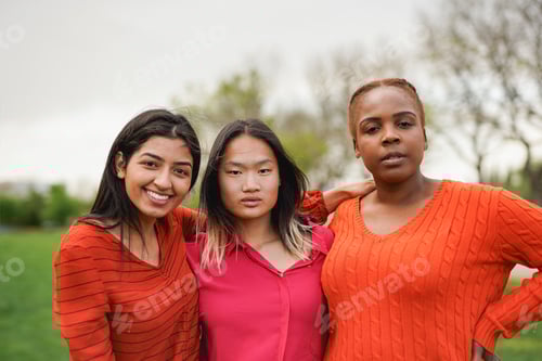 Preview: Group of diverse young women looking at camera - Multiracial female friends at city park