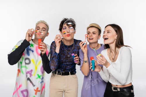 Preview: joyful lgbtq community friends having fun and blowing soap bubbles isolated on grey