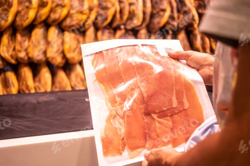 Preview: Female hands hold a package of freshly cut cured ham in the charcuterie shop