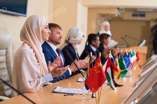 Preview: Young female delegate in hijab and her foreign colleagues applauding