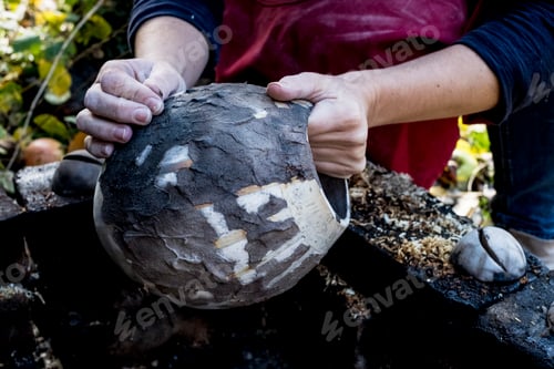 Preview: High angle close up of ceramic artist sitting outdoors, working on vase.