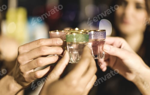 Visualização: Um grupo em uma festa segurando copos de shot e comemorando.