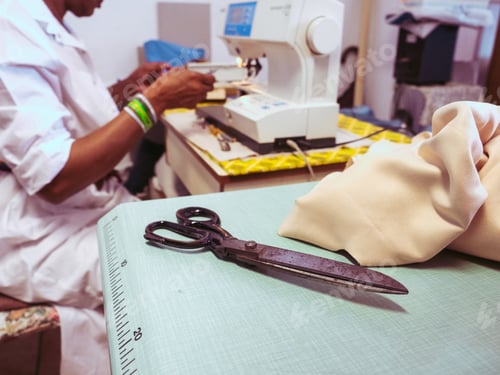 Preview: close up of adult black seamstress use sewing machine to skillfully sew a shirt with precision care
