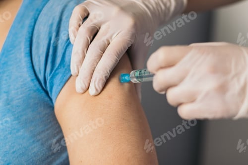 Preview: Doctor hands injecting vaccine in the arm of a patient.