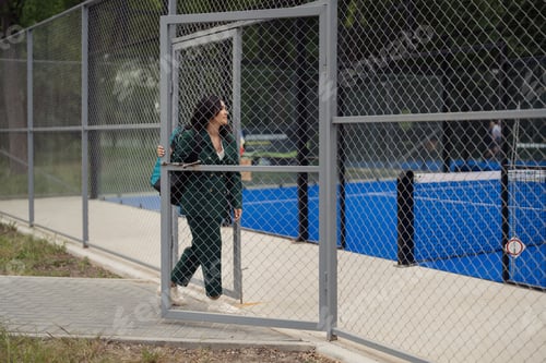 Preview: Woman entering padel tennis court in green suit