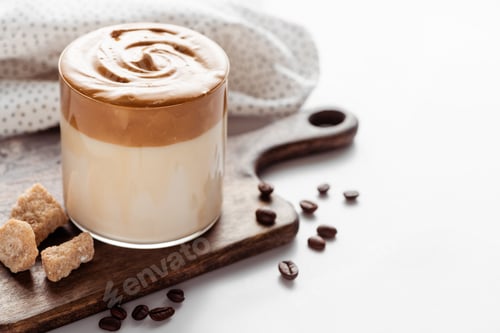 Preview: Delicious Dalgona Coffee in Glass Near Coffee Beans, Brown Sugar on Cutting Board And Napkin