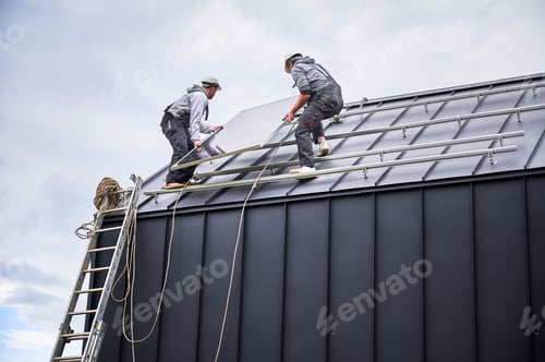 Preview: Technicians carrying photovoltaic solar module while installing solar panel system on roof of house