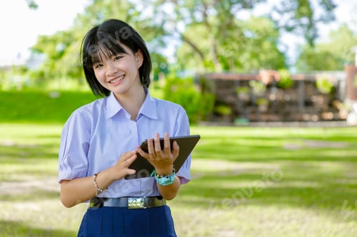 Preview: Portrait Asian student school teen girl in uniform at green park outdoor with tablet computer