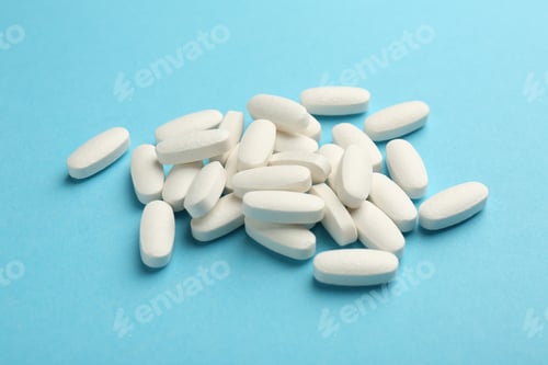 Preview: Pile of vitamin pills on light blue background