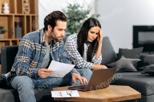 Preview: Frustrated caucasian couple sitting on the couch, the guy and the girl are freelancers, work from