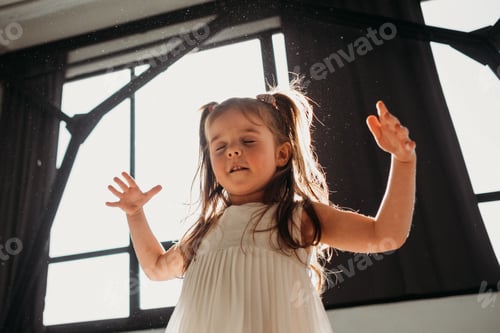 Preview: Cheerful little girl playing in sun light at home