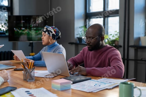 Preview: Young serious economist in purple pullover typing on laptop keyboard
