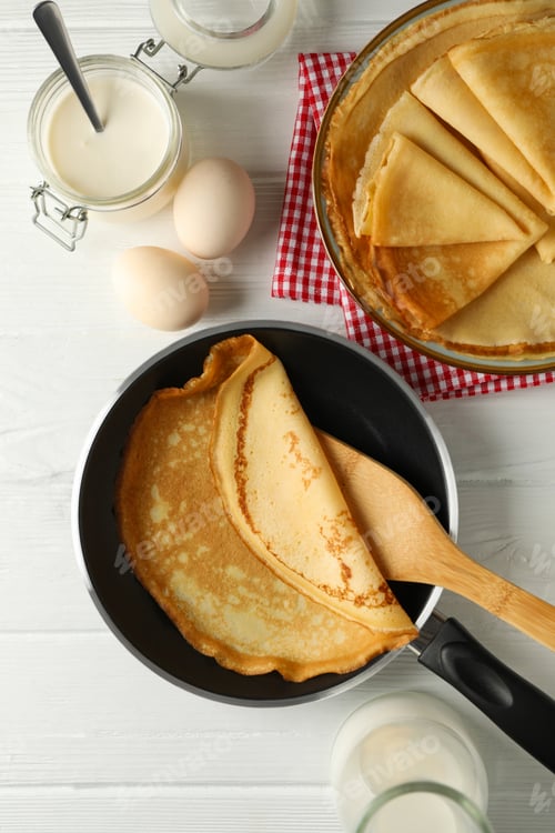 Preview: Concept of tasty breakfast with thin pancakes on white wooden table