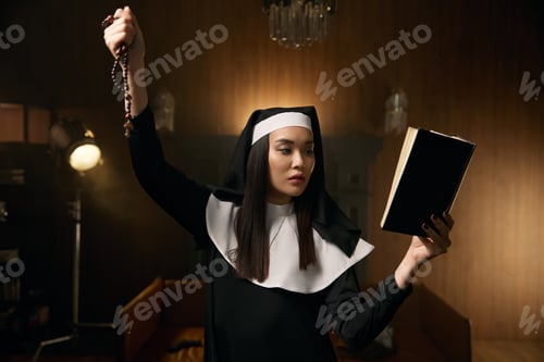 Preview: Young nun praying with bible and beads with crucifix