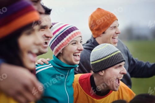 Preview: Group of men and women friends cheering at an informal sporting event in winter.
